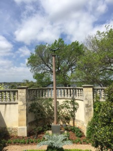 A secret garden features a sculpture atop a tall pole.