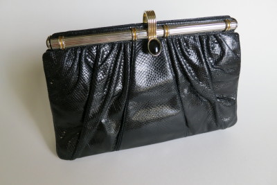 The black snake bag is detailed with silver and gold hardware and an onyx stone on the clasp.