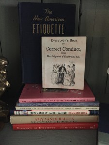 A few etiquette books displayed in a hutch.