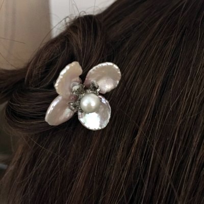 This hair pin is 10 kt white gold with pearl petals and center. It has exquisite detailing in the gold.