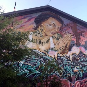 A mural outside Manuela Restaurant is the backdrop for outdoor seating, vegetable and herb gardens and chicken coops.