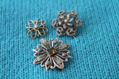 A grouping of filigree pins on a sweater.
